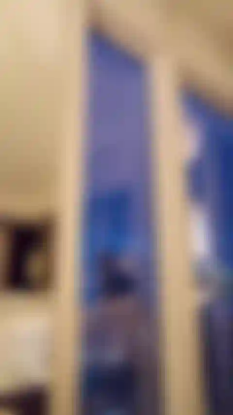 Un juguete elegante muestra su cuerpo a la ciudad en la ventana de un hotel de gran altura.