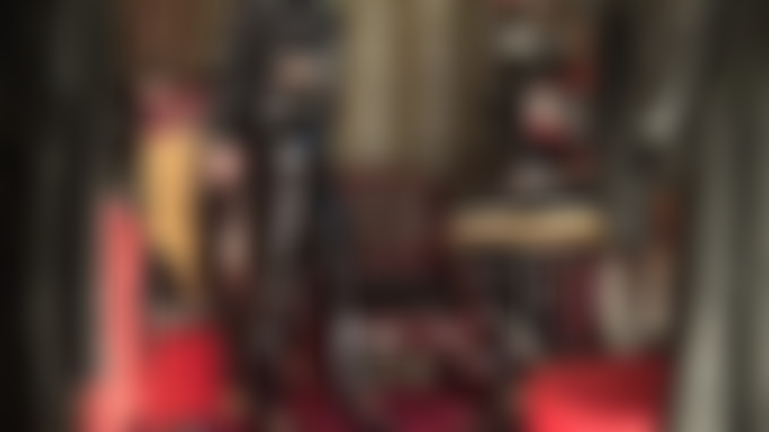 Fetichista del pvc, completamente vestida con vinilo negro brillante, la amante provoca al fetichista del pvc con jeans brillantes, tacones y abrigo largo.