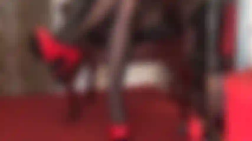 Tacones rojos brillantes, guantes de cuero negro y piernas en medias negras son pura seducción.