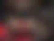 Guantes de cuero rojos sobre un enorme strap-on negro.