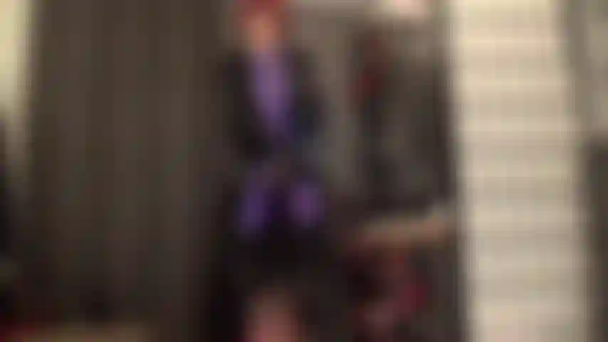 Abrigo pesado de pvc brillante sobre traje leohex morado con correa stryker y botas.