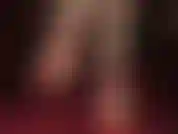 Fetichista de pies descalzos, con tacones de aguja y tiras rojas en el tobillo, colgando.