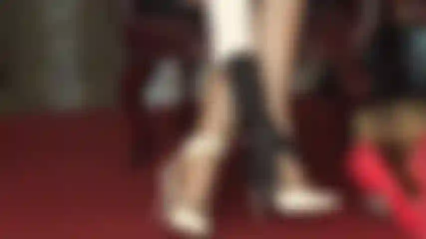 Sandalias blancas de tiras y medias brillantes que acarician los pies.