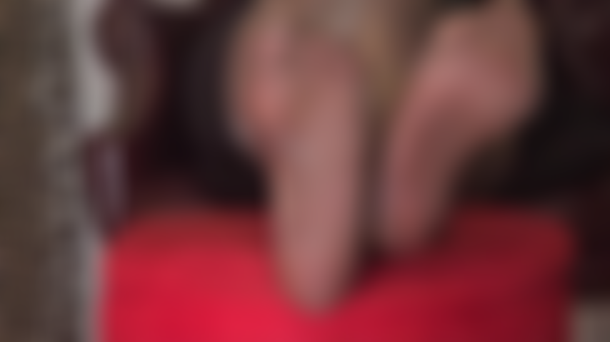 Fetichista de pies con tobillos cruzados, medias brillantes de color marrón oscuro y tacones brillantes con doble colgante.