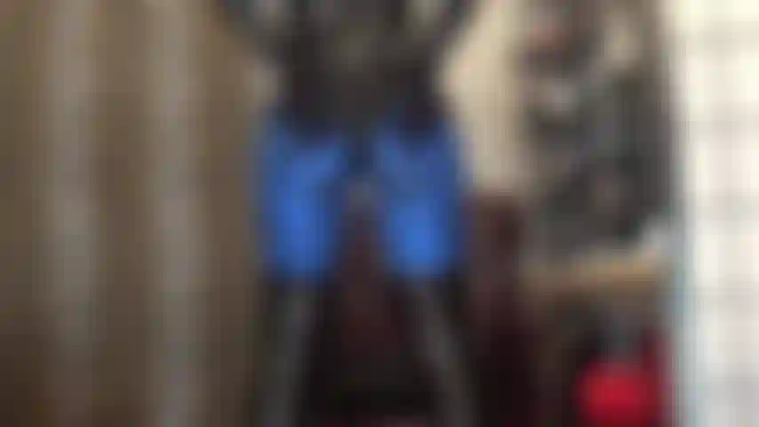 Culo en leggings de lycra azul metalizado y body de pvc brillante, pies en pantimedias marrón oscuro.