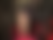 Medias sexys color piel, cabello negro, cuero negro, body rojo y tacones de aguja con tiras rojas en el tobillo.