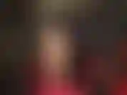 Medias sexys color piel, cabello negro, cuero negro, body rojo y tacones de aguja con tiras rojas en el tobillo.