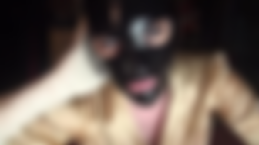 Fetichista del látex: capucha de goma negra brillante y guantes de látex blancos.