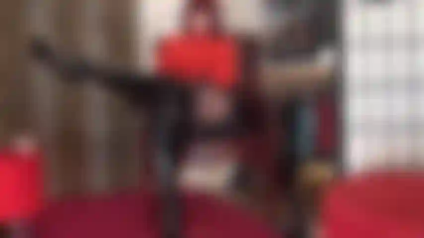 Adoración al cuerpo con este sexy atuendo de body rojo, falda de vinilo brillante, pantimedias negras y botas altas hasta la rodilla de charol negro.