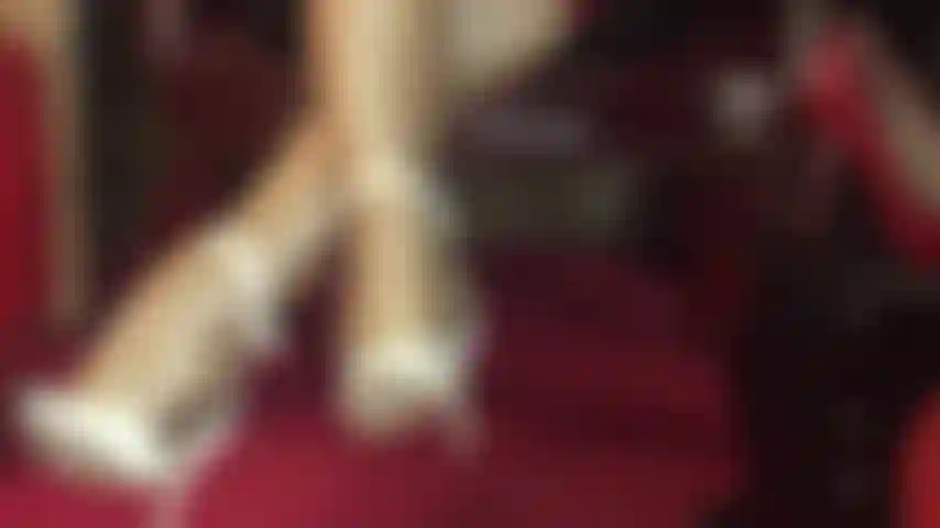 Increíbles piernas en pantimedias brillantes con capas de nailon dorado y sandalias blancas con tiras en el tobillo.