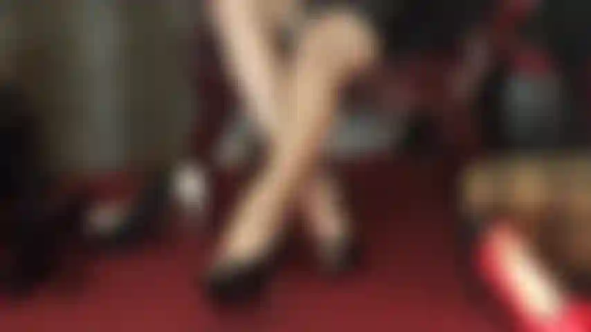 Pura seducción, piernas largas cruzadas que se cierran y abren en medias de alto brillo, otorgando vistas tentadoras en el medio.