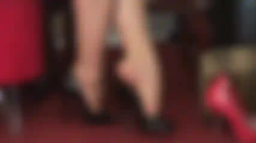 Fetichismo de pies, adoración de tacones altos, colgando: hermosos peeptoes negros brillantes cuelgan de los dedos de las pantimedias de la amante.