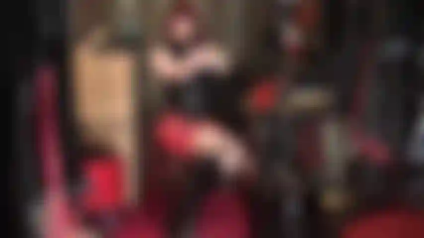 Fetichista del látex: traje de goma rojo y negro con botas hasta la rodilla.