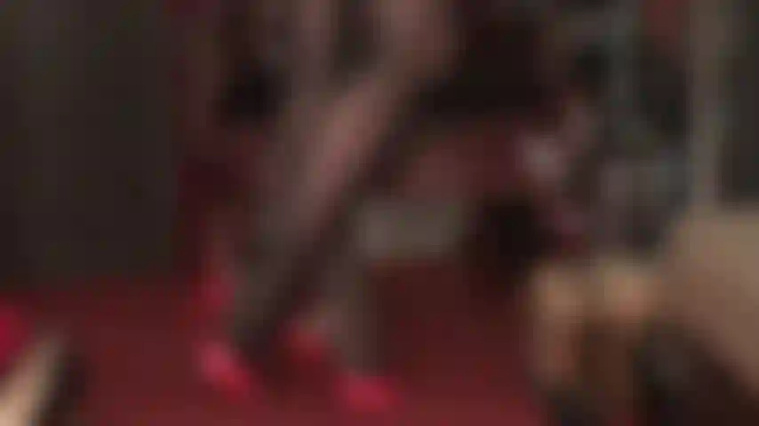 Medias negras brillantes con acabado aceitado y mules rojos de tacón alto.