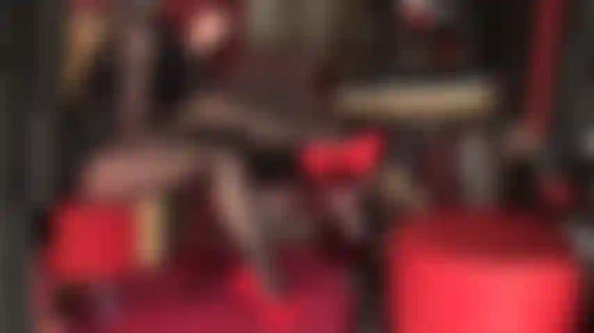 Con piernas provocativas, medias negras brillantes de varias capas, cuero y tacones de aguja rojos. Piernas cruzadas, lápiz labial negro y tacones rojos intensos.