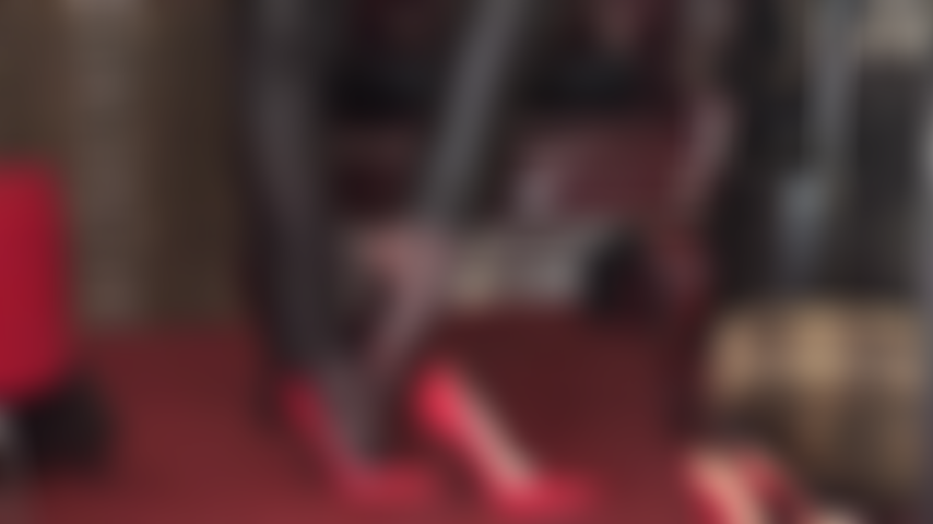 Fetichista de pies y adoración de tacones altos: pantalones de cuero y tacones de aguja rojos y medias de red para provocar los pies.