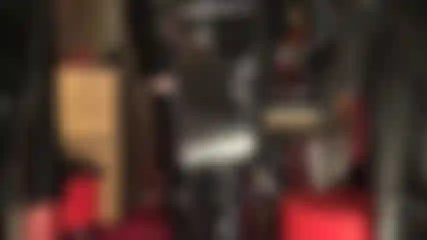 Amante fetichista de pvc brillante con fusta y botas por encima de la rodilla.