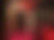 Provocación sensual y adoración al cuerpo en rojo y negro: la amante usa un vestido sexy con corsé de cuero, medias brillantes color piel y tacones rojos brillantes.