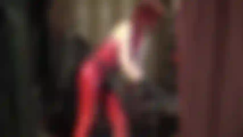 Arnés negro enorme y catsuit de goma rojo.