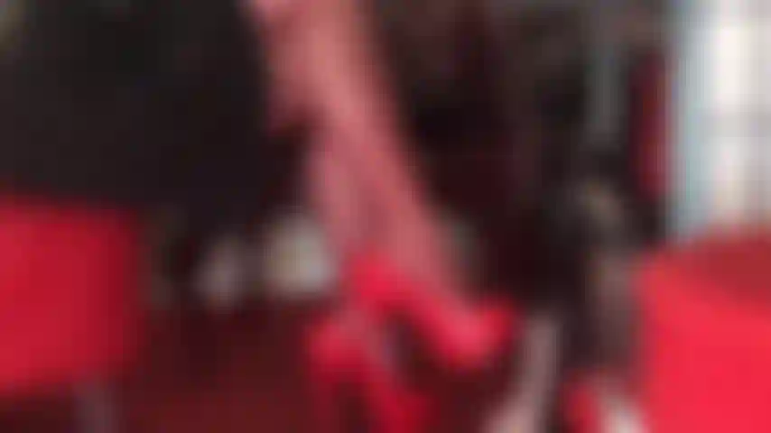 Piernas cruzadas seductoras con medias rojas y tacones rojos brillantes provocan la dolorida polla del esclavo.