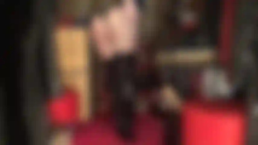 Una diosa que adora el culo, vestida con un traje de tanga de pvc negro brillante y botas altas sobre medias negras transparentes.