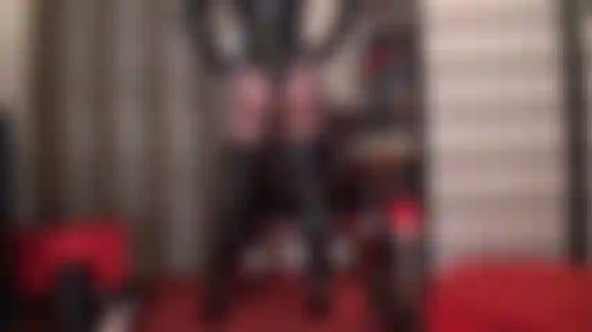 Curvas brillantes de perfección: una seductora brillante muestra sus curvas de perfección en un traje de baño de pvc con tanga, botas altas hasta la rodilla y pantimedias negras transparentes.