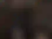 Traje de látex negro, arnés blanco y máscara de pantimedias.