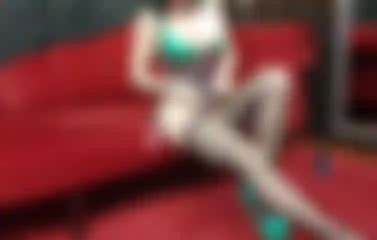 Burlándome con corselet de látex y medias de rejilla, mostrando el coño.