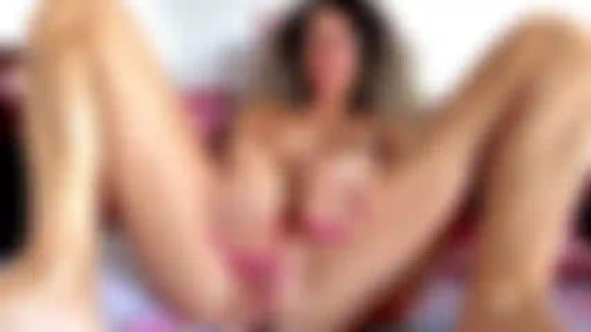 Abro los grandes labios de mi coño, provocando mi clítoris duro, recostada, completamente desnuda, con las piernas bien abiertas, mostrando mi coño mojado y mis grandes pezones.
