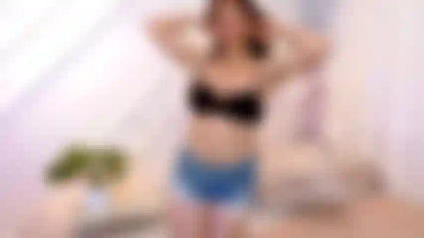 Striptease sensual y masturbación con piernas abiertas en la cama.