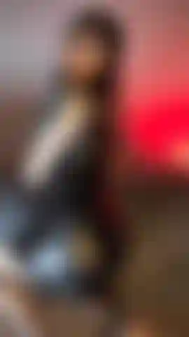 Una chica sexy tatuada con vestido de cuero negro, medias de rejilla y azotes en el culo.