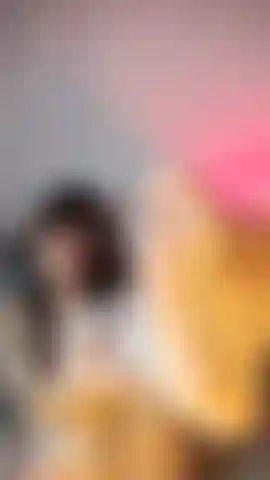 Una nena en lencería blanca con medias de rejilla, acariciando sus pies y sonriendo juguetonamente a la cámara.