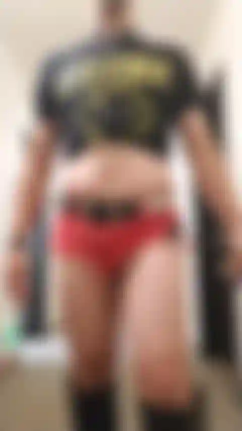 Crossdresser posando sexy en el pasillo del hotel con pantalones cortos de jean y botas.